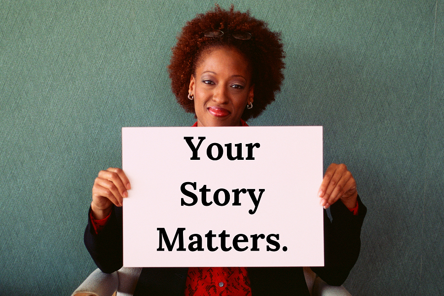 a woman holding a sign that says "your story matters"