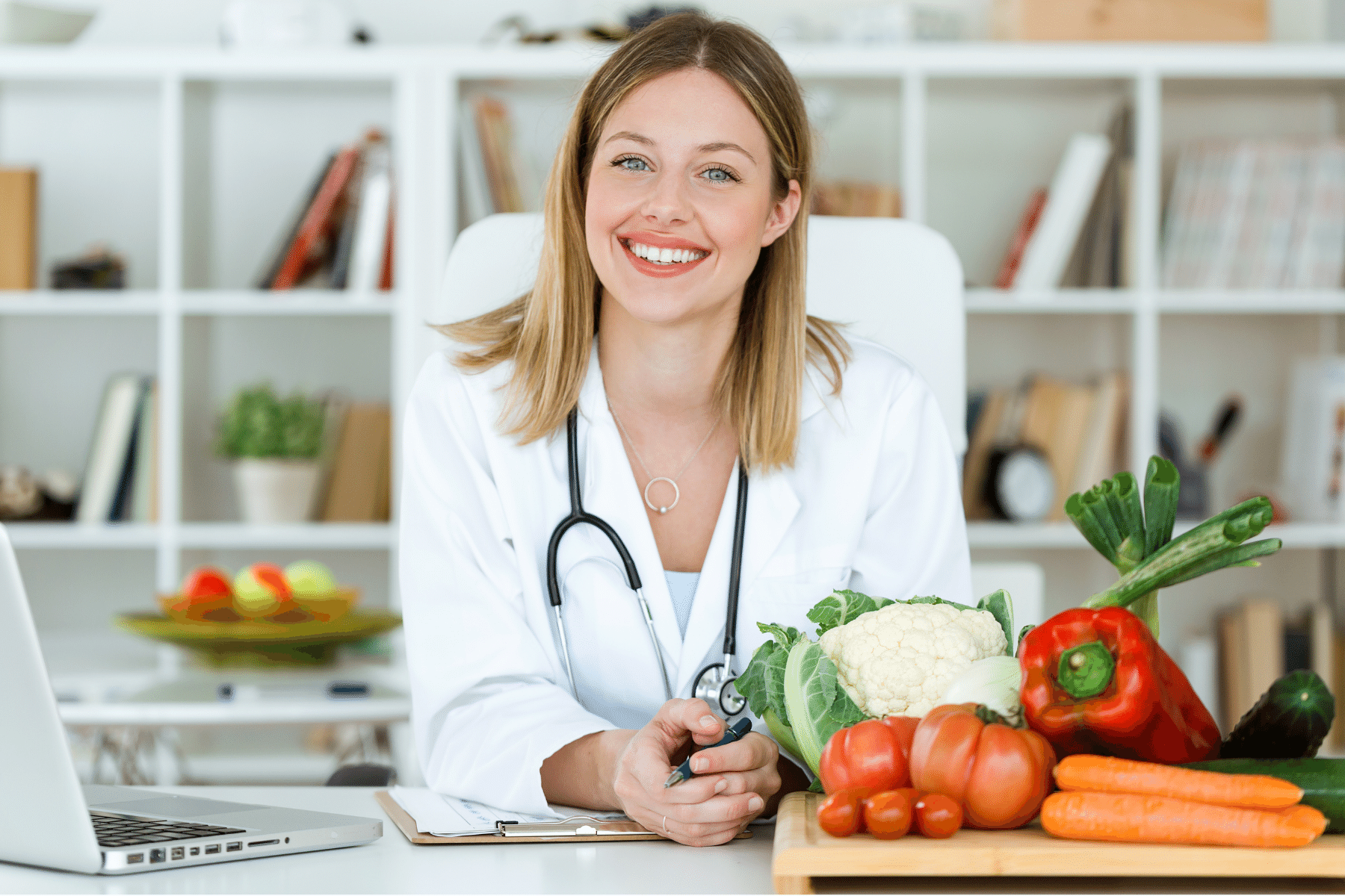 photo of a person in a lab coat with stethoscope holding a tray of fruits and vegetables