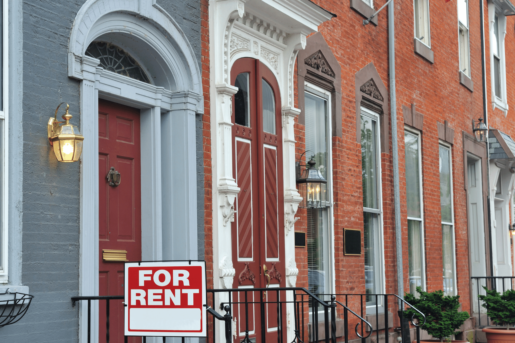 picture of an apartment building with a "for rent" sign in the bottom window