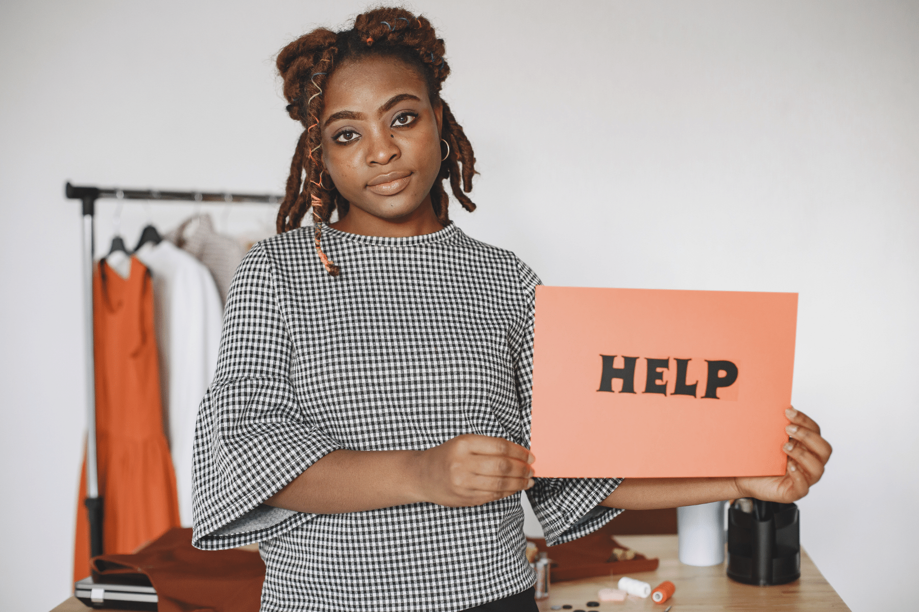 black woman holding up a sign that says help
